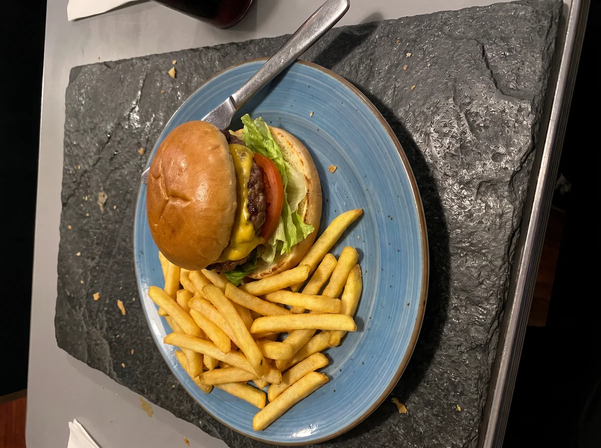 Hamburguesa sobre una losa de piedra que deja parte de la mesa visible